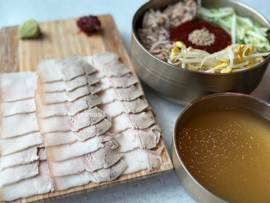 Table setting with dongchimi bibim noodles and dombe naengsuyuk