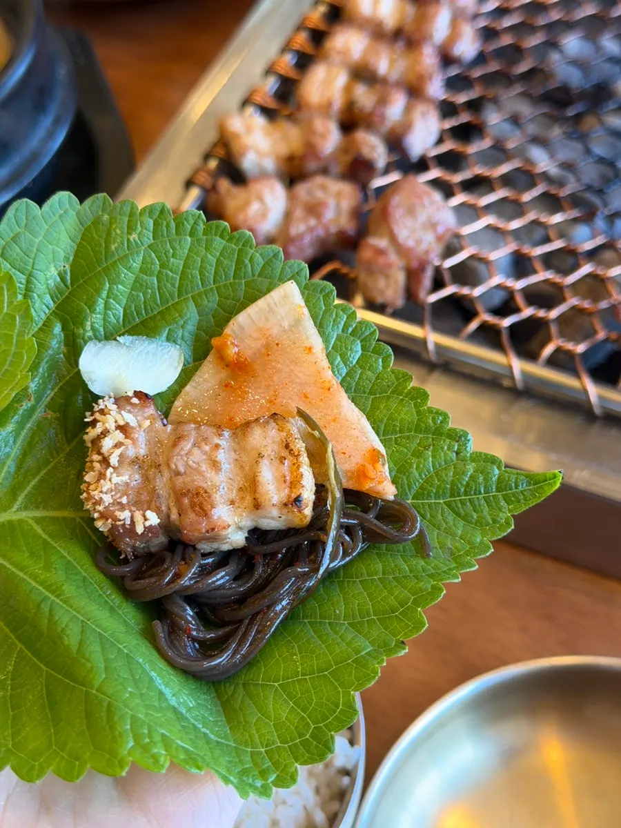 A bite of black pork with a bite of hoe naengmyeon