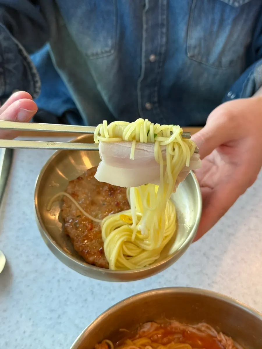 Rich bone broth pork noodles served in a brass bowl
