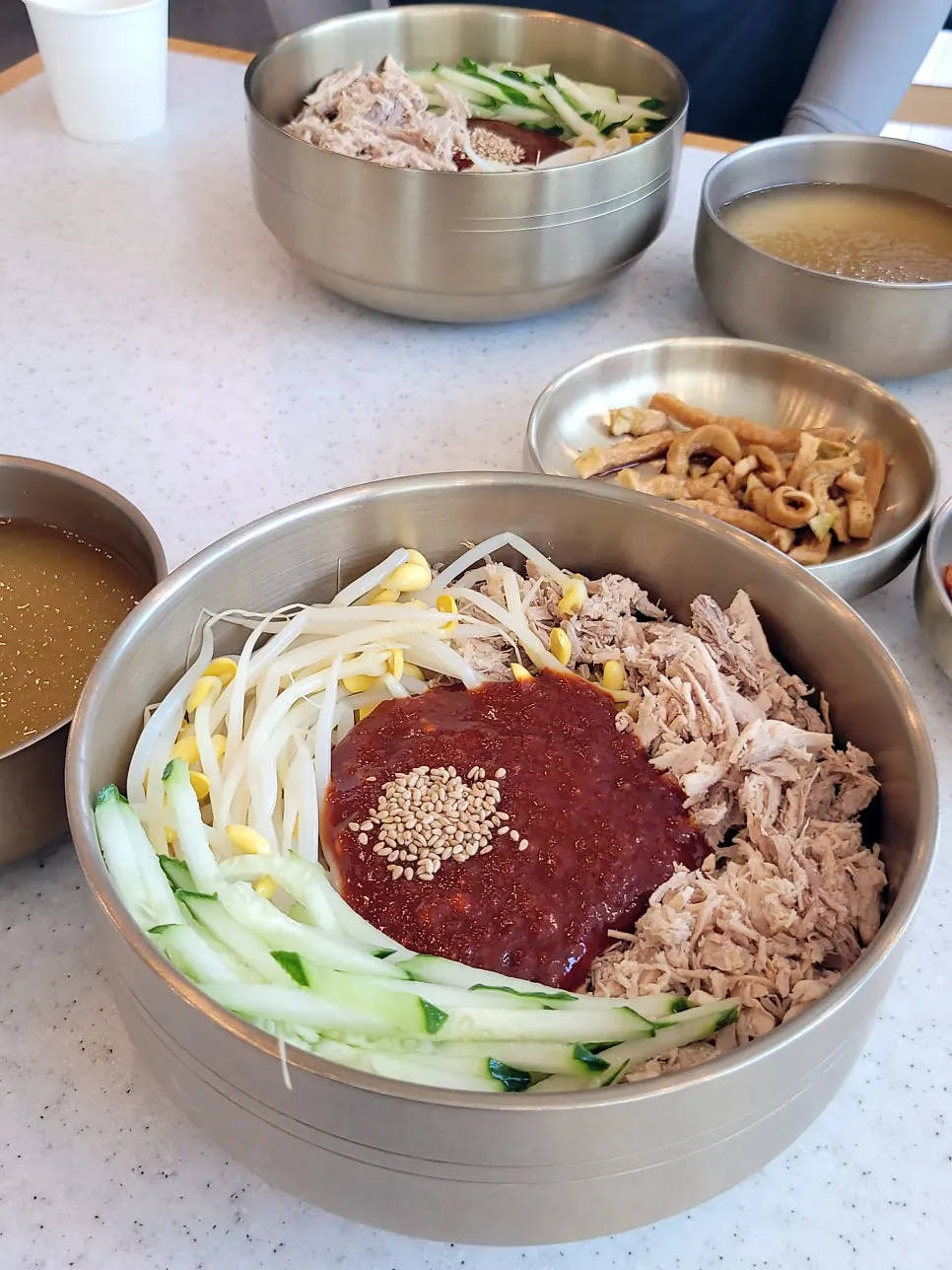 Dongchimi bibim noodles topped with cucumber and shredded meat