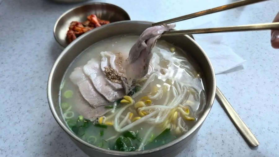 Noodles lifted up out of the rich bone broth