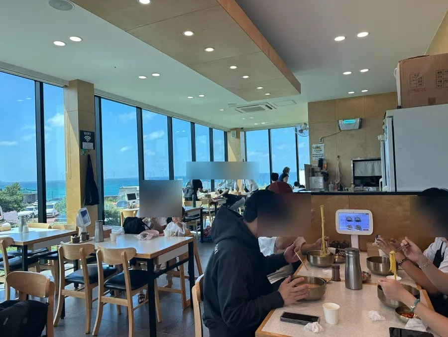Restaurant interior with floor-to-ceiling windows showing sky and sea