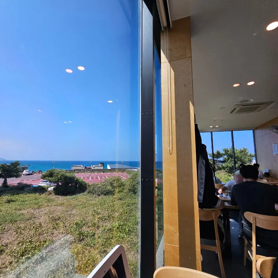 Restaurant interior with the Aewol sea visible through floor-to-ceiling windows