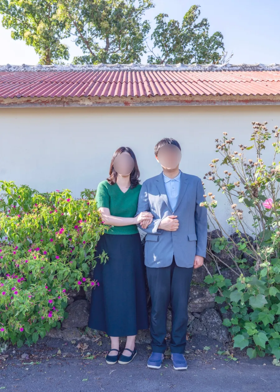 Couple snap with a Jeju stone wall and old roof background