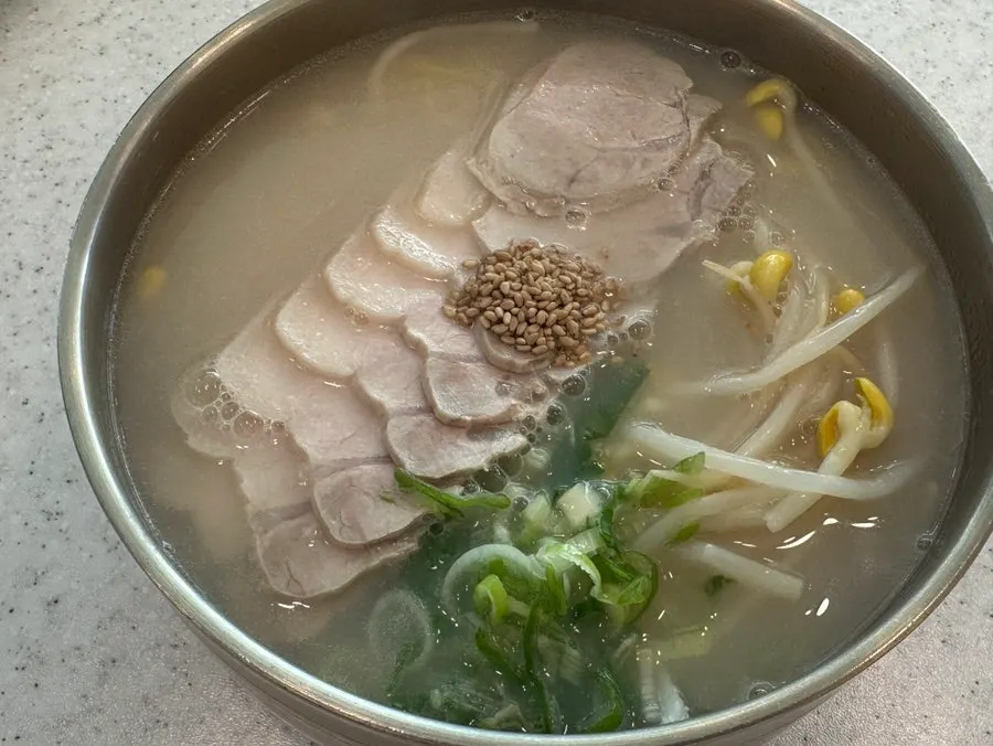 A bowl of bone-broth pork noodle soup topped with garnish