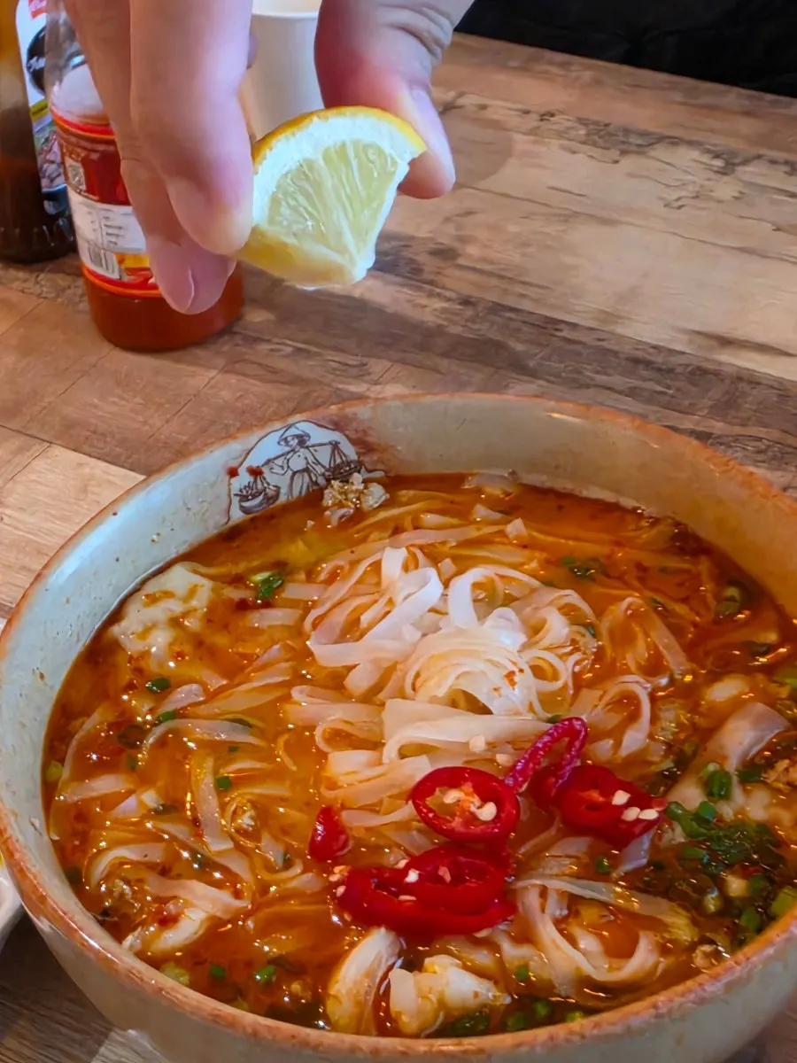 Noodles lifted with chopsticks from the tom yum pho