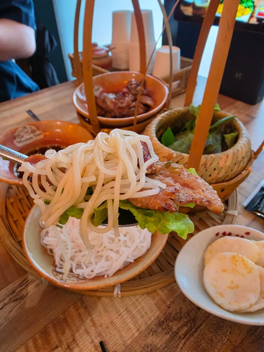 Noodles, vegetables, and pork arranged on a small plate with sauce poured over