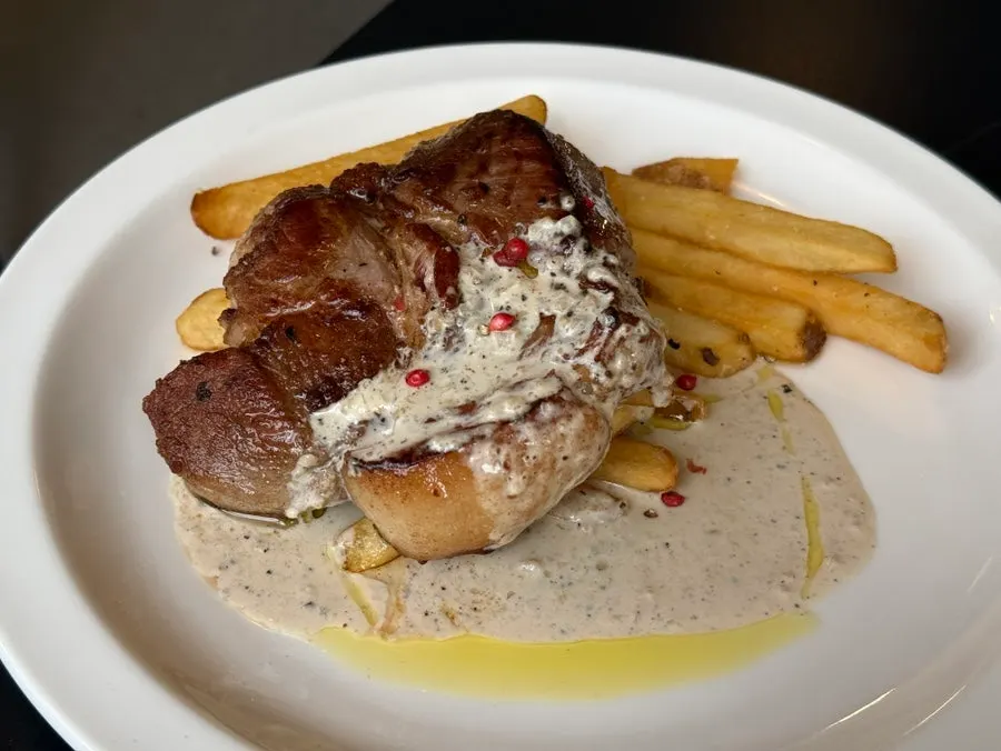 Plate of sous-vide pork shoulder steak with fries