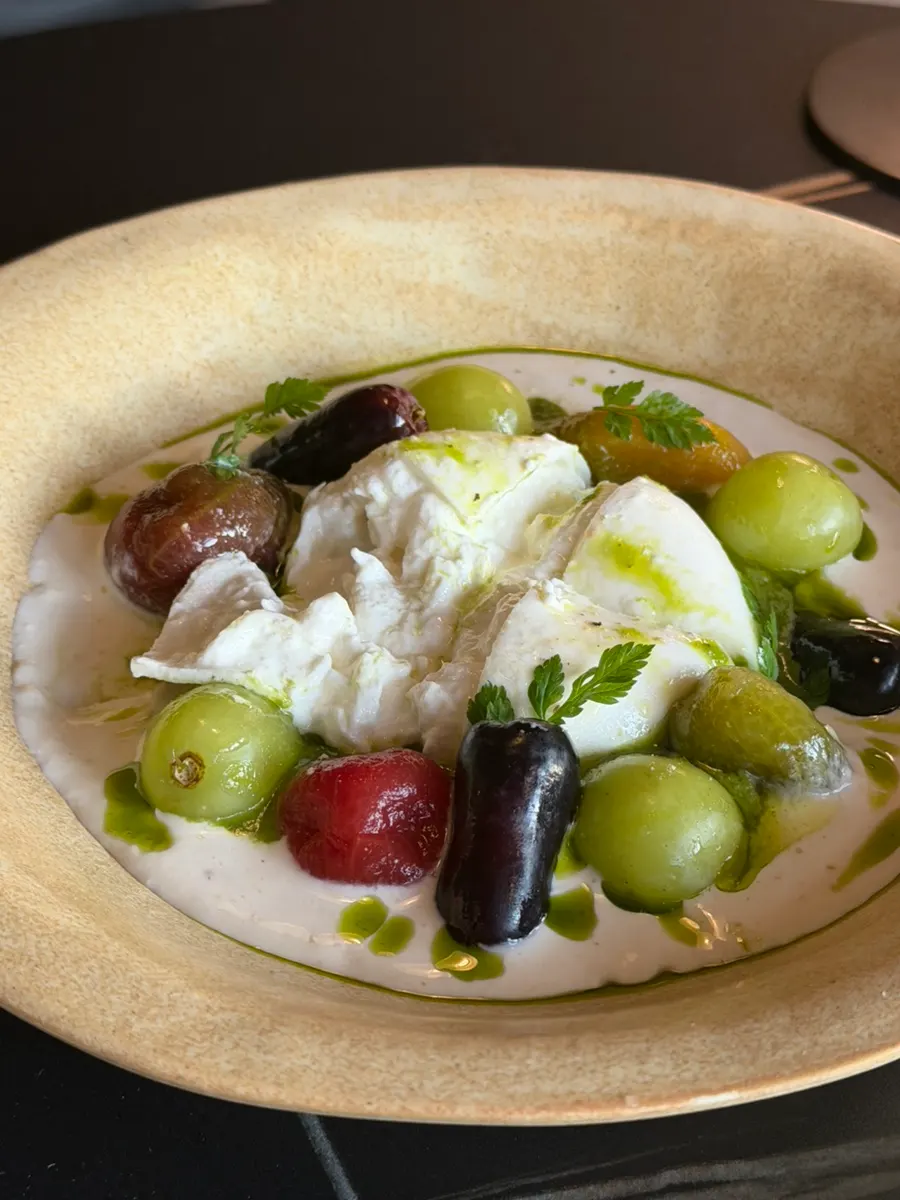 Burrata salad topped with seasonal fruit and cherry tomatoes
