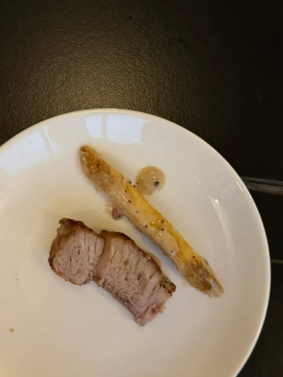 A bite of pork neck steak dipped in pepper cream sauce