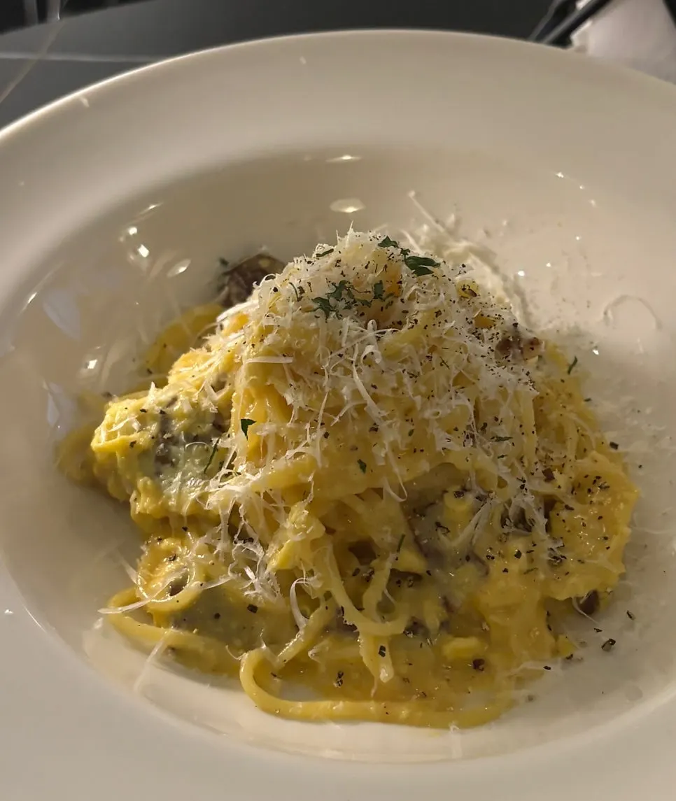 Carbonara topped with guanciale and an egg yolk