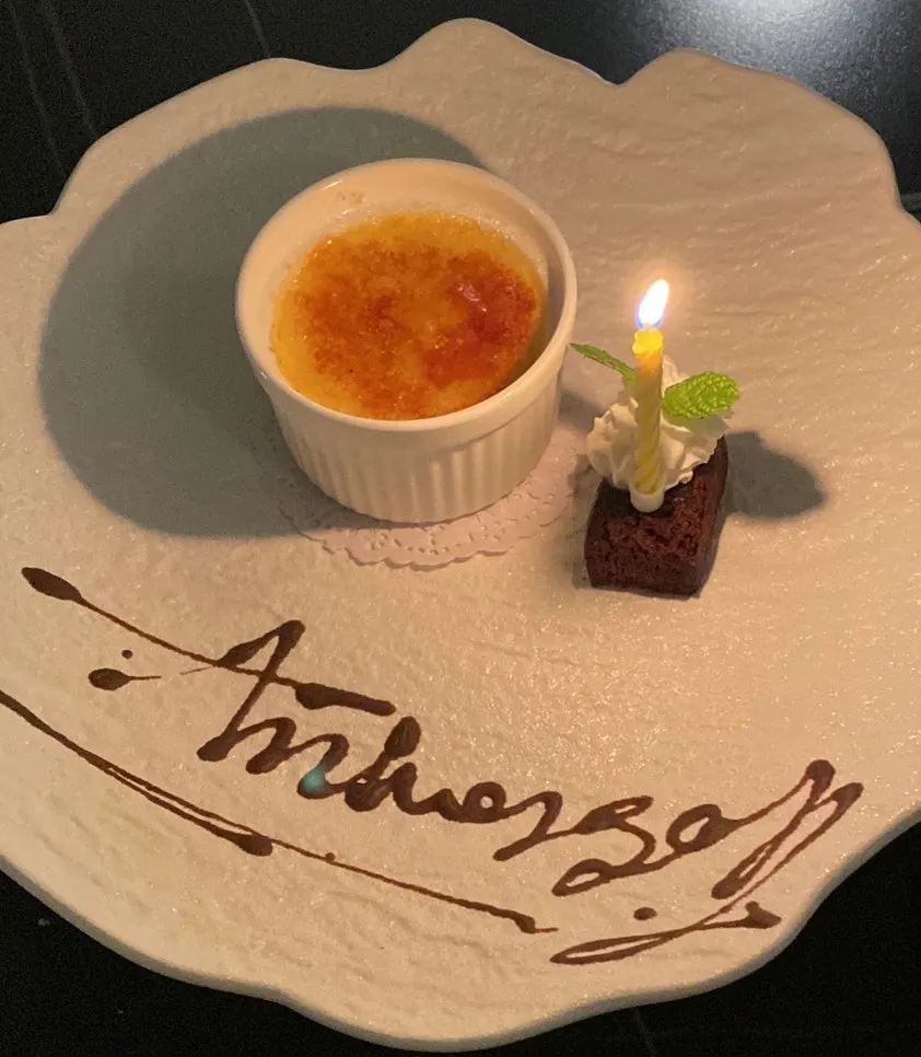 Plate with a lit candle for the one-year anniversary lettering dessert