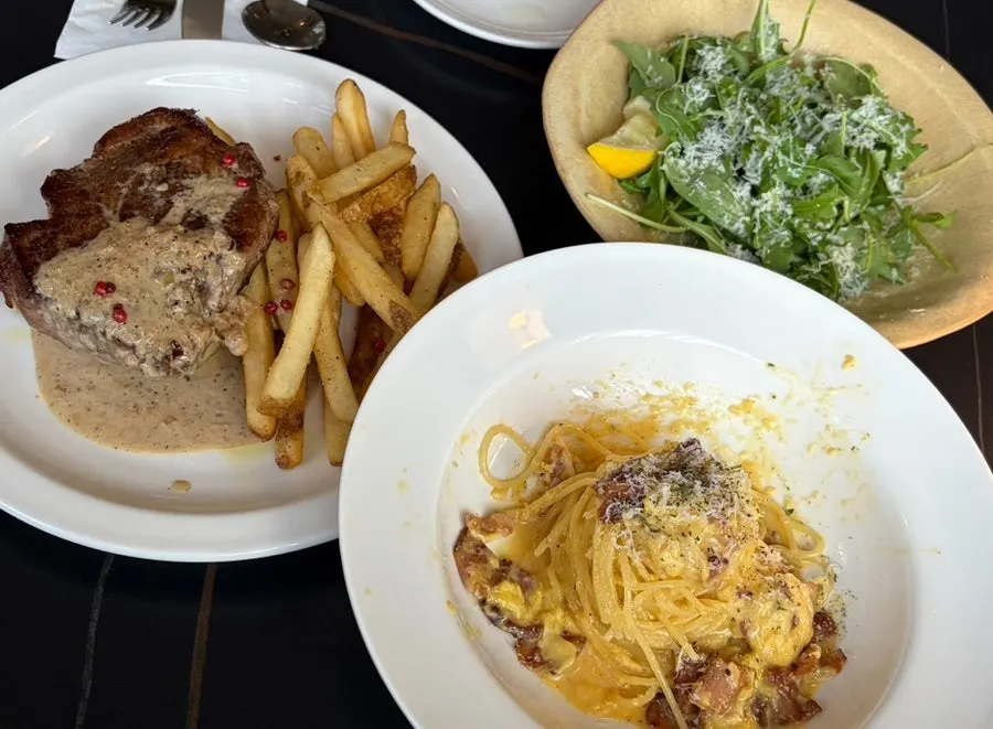 Mesa servida con bistec, pasta y ensalada pedidos
