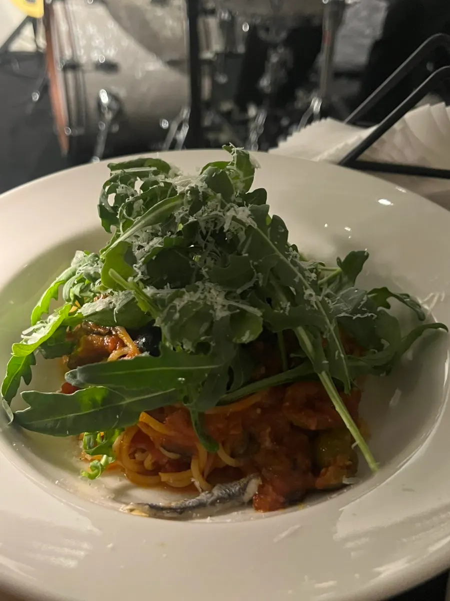 Puttanesca pasta piled high with arugula