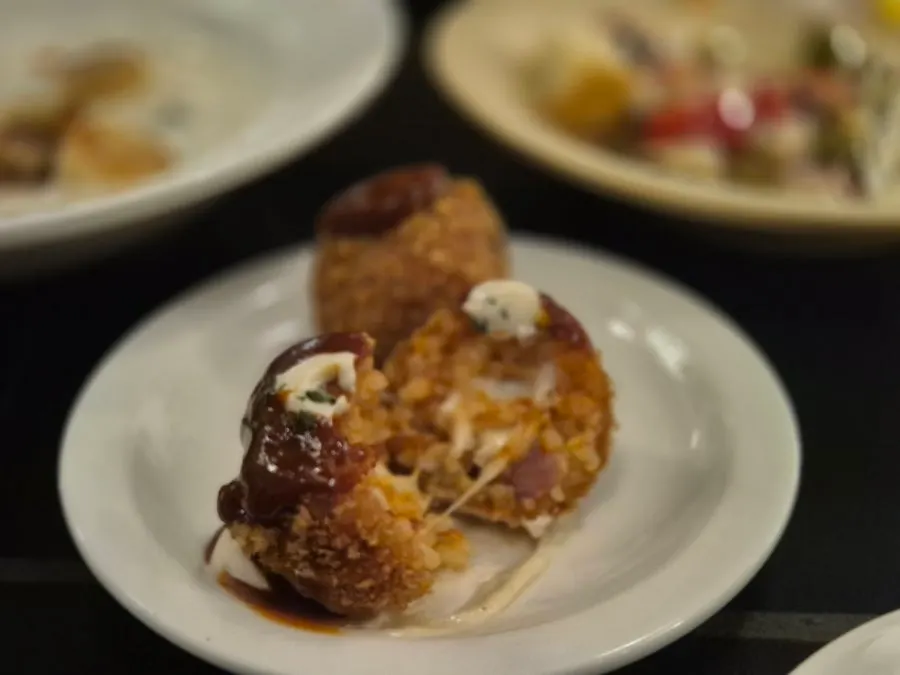 An arancini cut in half showing stretchy cheese inside