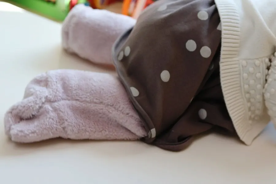 An 8-month-old baby wearing foot warmers