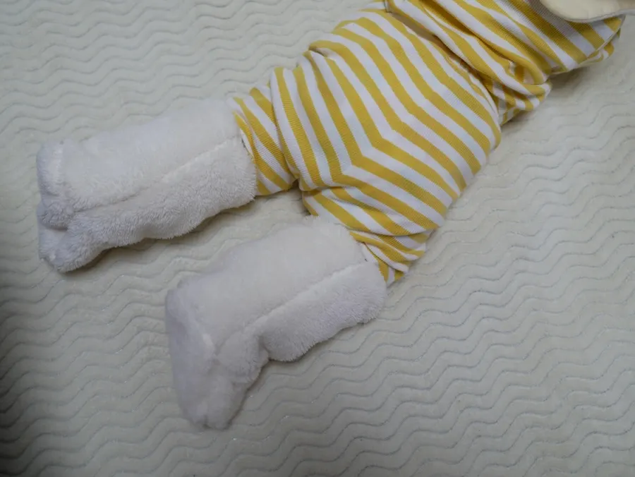 A 6-month-old wearing white foot warmers