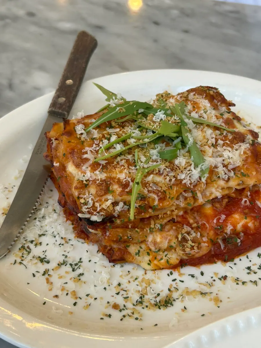 Lasagna topped with arugula and parmesan cheese