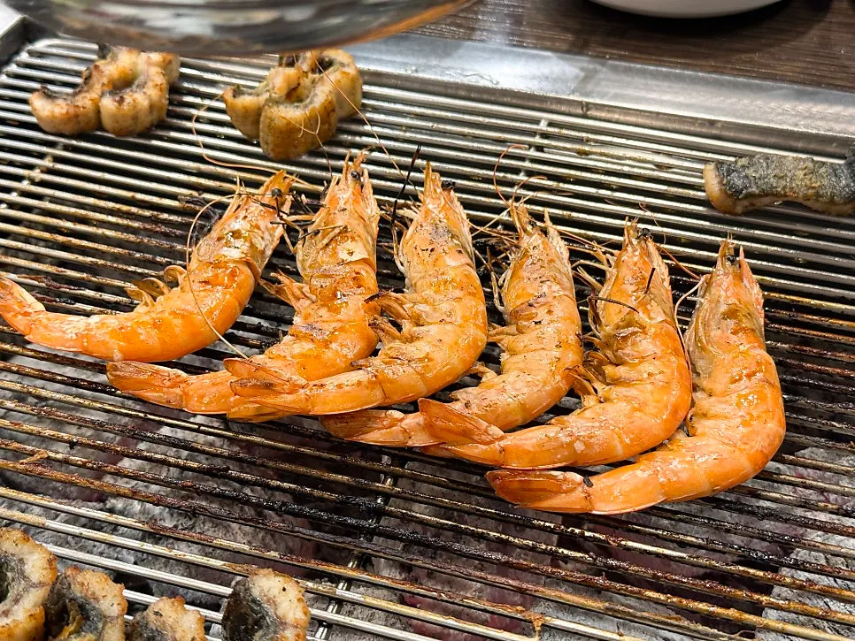 King prawns lined up and grilling over charcoal