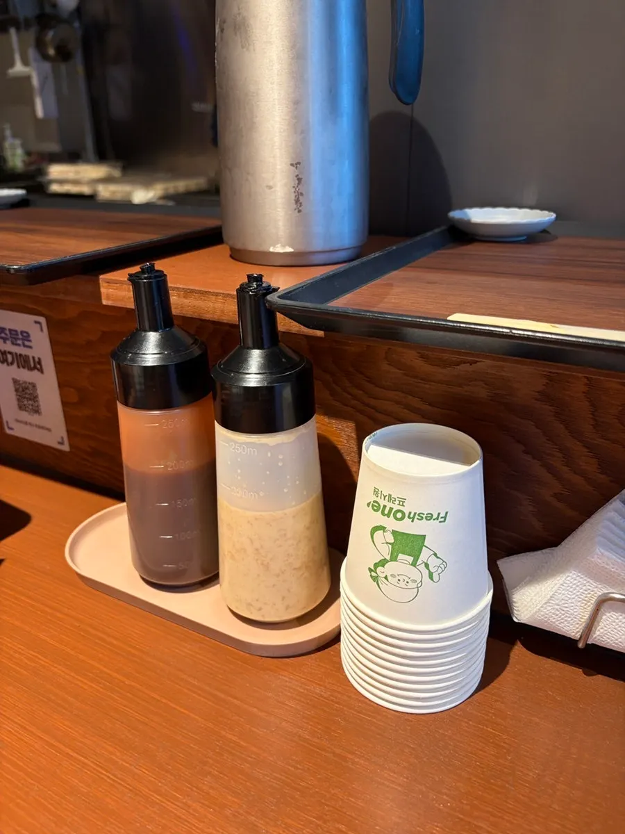 Sauce bottles, pitcher, and paper cups on the counter