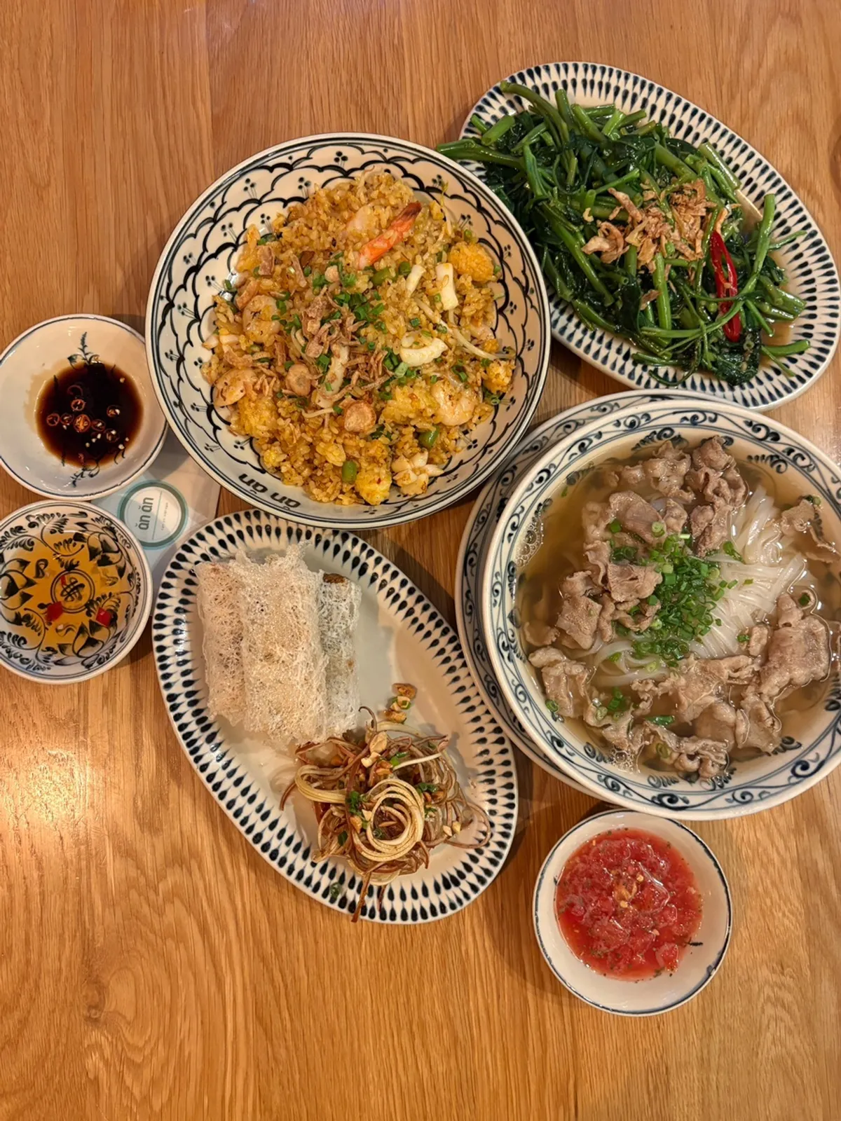 A table for two set with pho, spring rolls, and fried rice