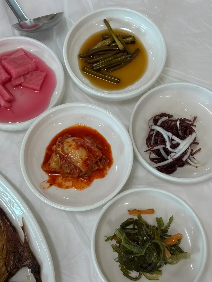 Side dishes like garlic scapes and kimchi served first after ordering