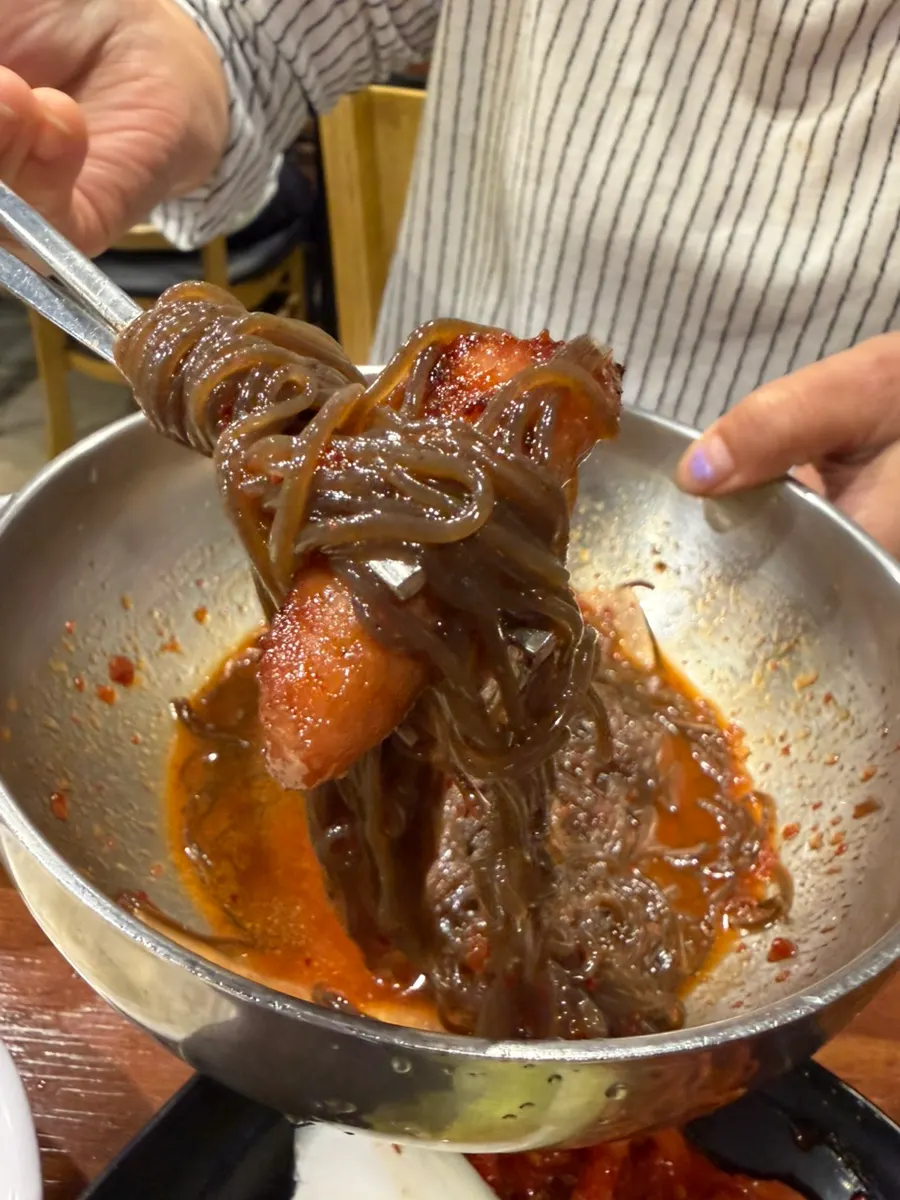 ビビン冷麺と豚カルビを一緒に包んで食べる様子