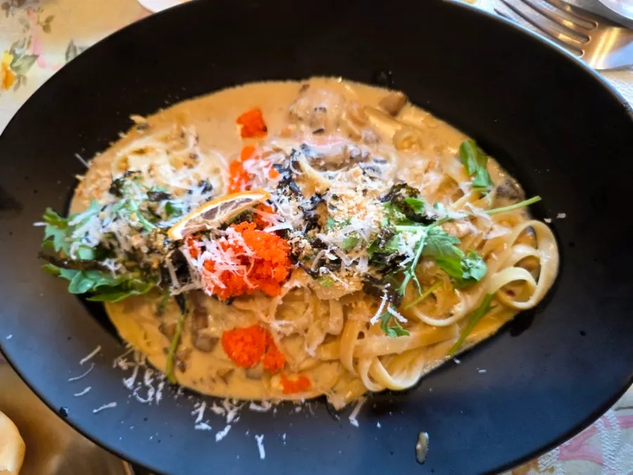 Snow crab guts cream pasta served on a black plate