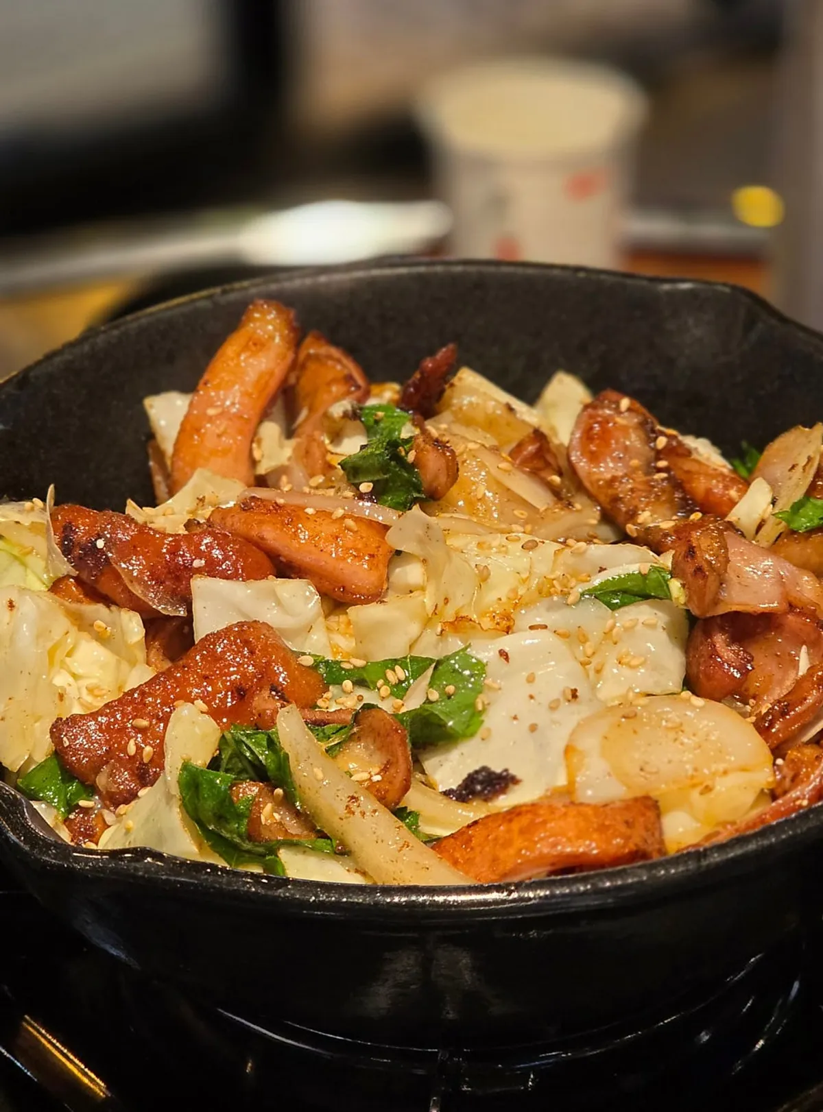 Salt-grilled makchang topped with onion, cabbage, and perilla leaves