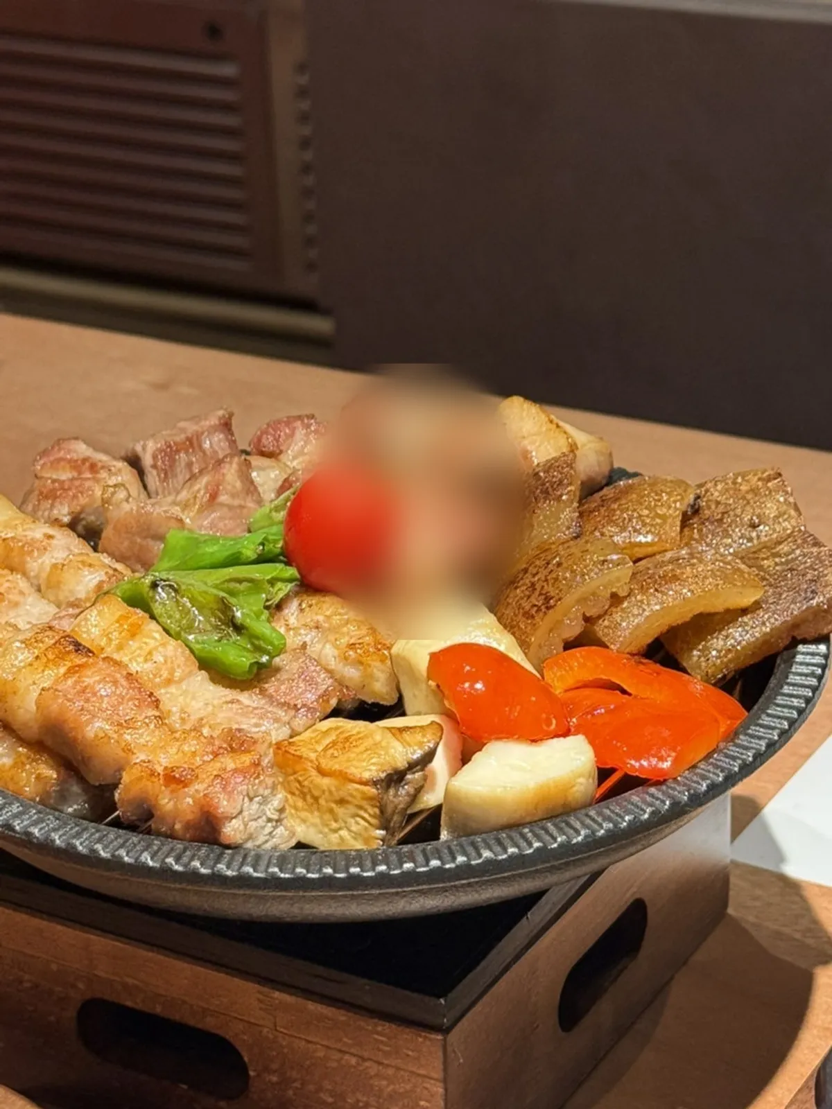 Grilled meat served in a bowl over a warming flame