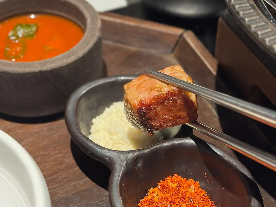 A piece of grilled pork belly dipped in salt