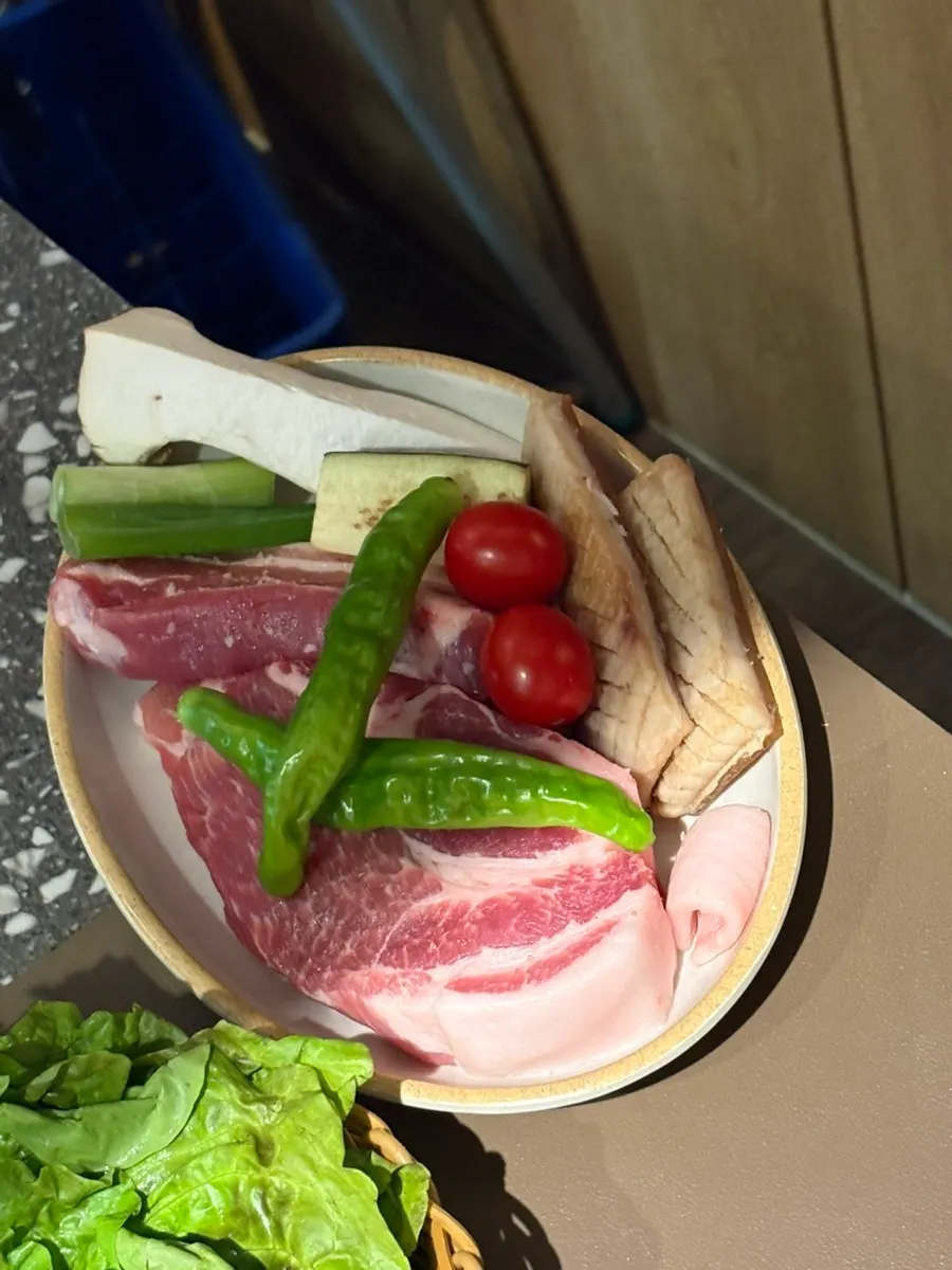 Basket of ssam vegetables with lettuce, perilla leaves, garlic, and cheongyang chili