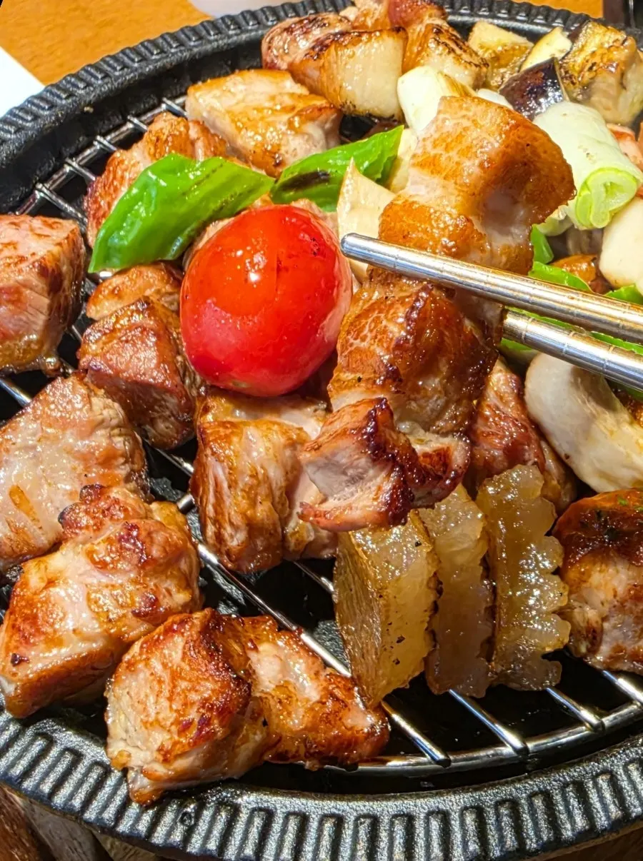 Staff member grilling meat over charcoal