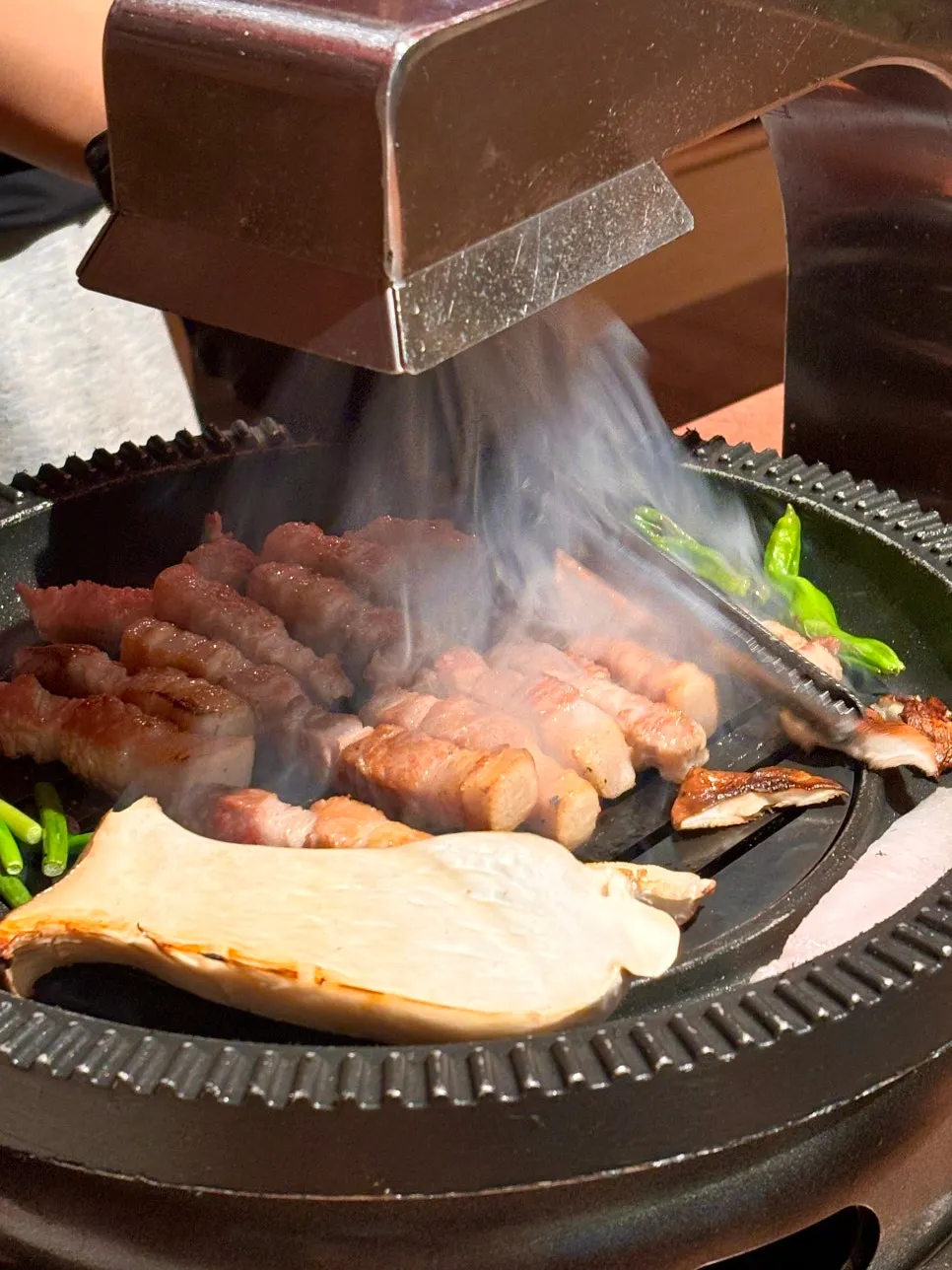 Whole pork belly grilling over charcoal