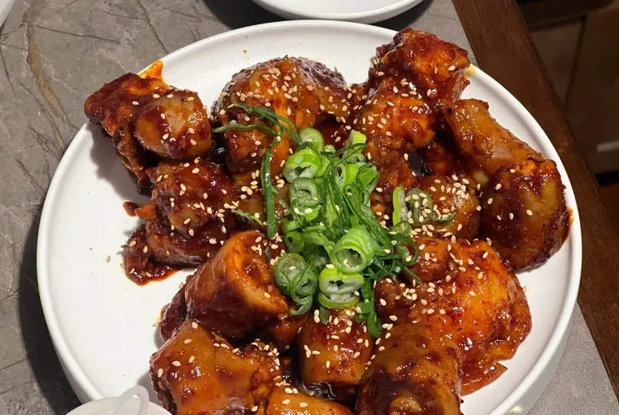 Pork tail jjim topped with red seasoning, sesame seeds and scallions