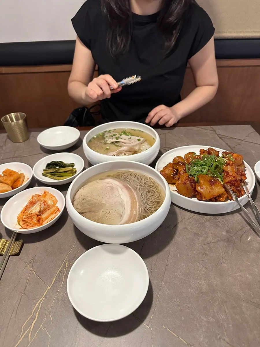 A table with gomtang, naengmyeon, and pork tail jjim