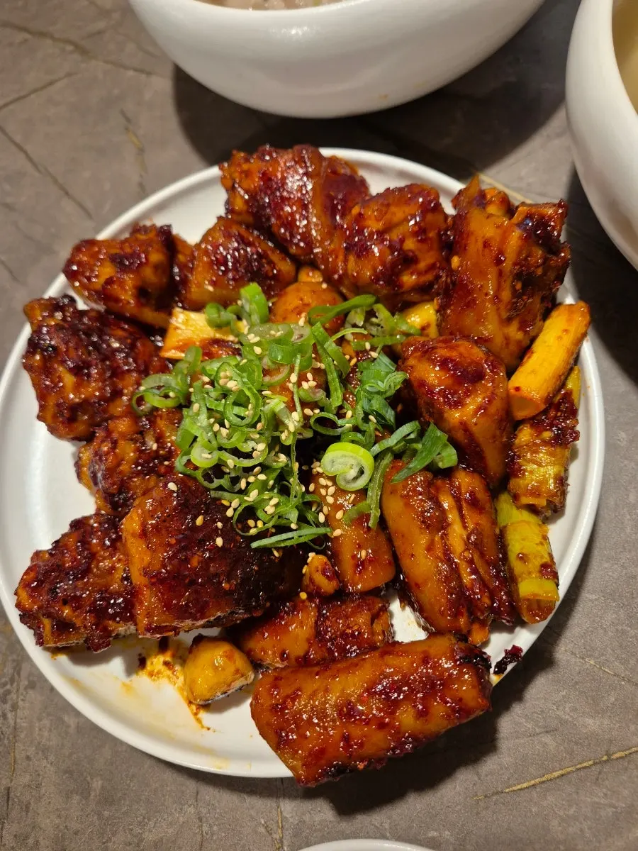 Plate of pork tail jjim with scallions and whole garlic