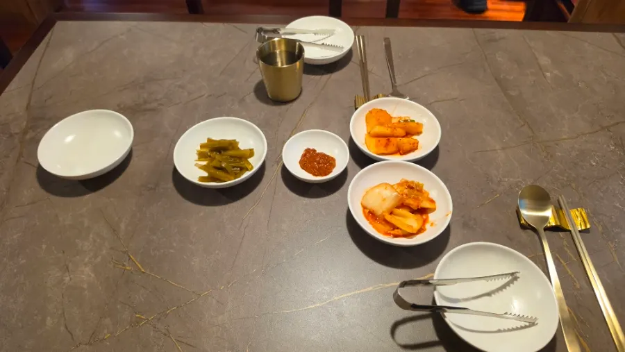 Basic side dishes: napa cabbage kimchi, cubed radish kimchi, pickled peppers, and ssamjang