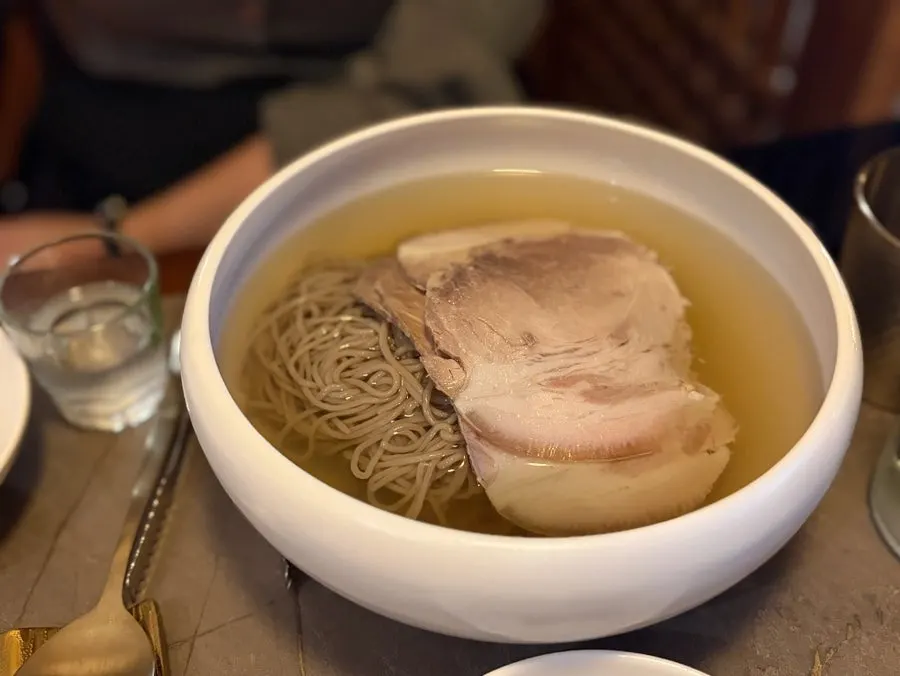 젓가락으로 들어 올린 메밀면과 맑은 육수