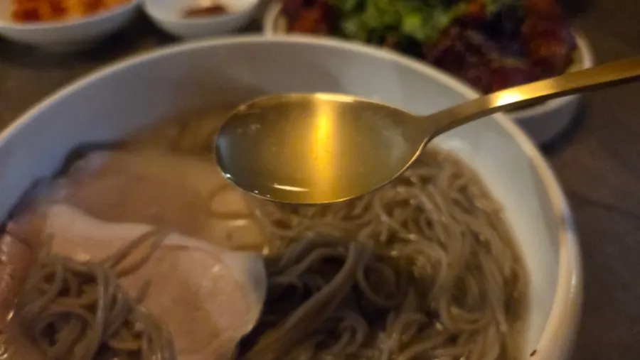 Wrapping meat around naengmyeon noodles to eat