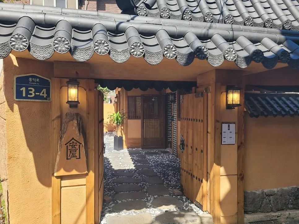 홍대 한옥 식당 안옥의 기와지붕과 나무 대문 외관