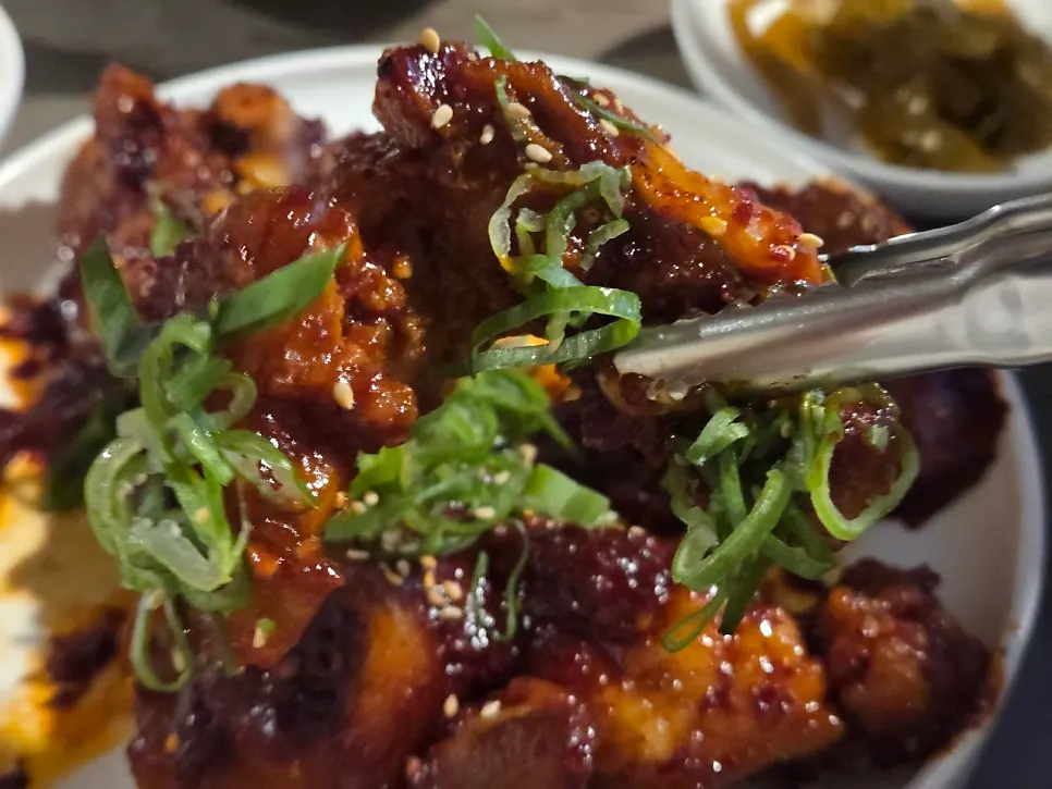 A chewy piece of pork tail jjim picked up with chopsticks