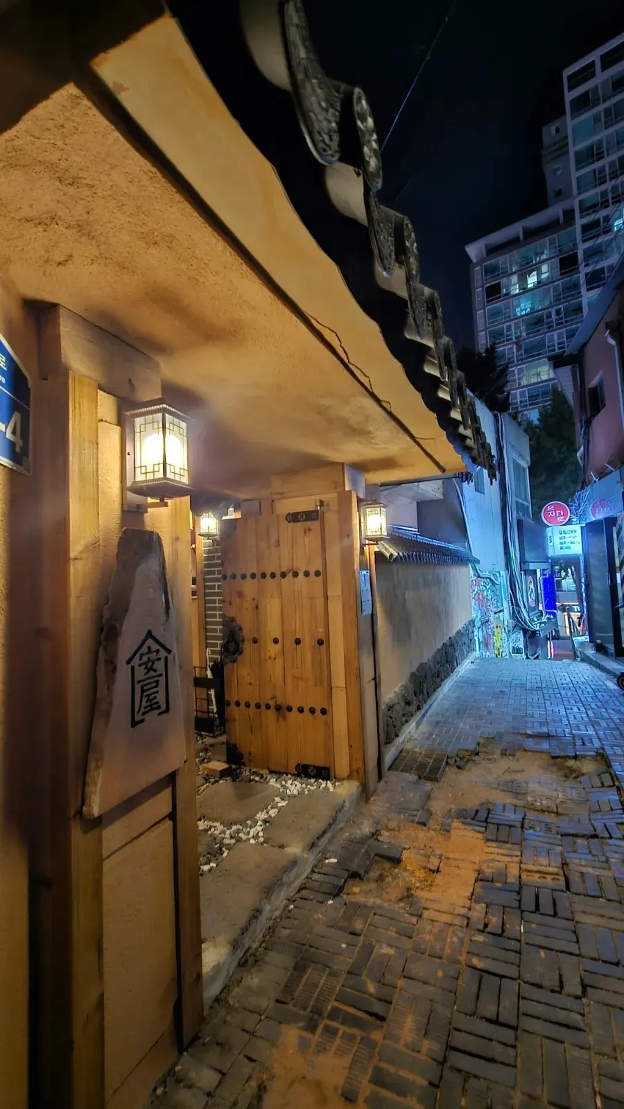 Anok's hanok-style exterior and wooden signboard in the night alley