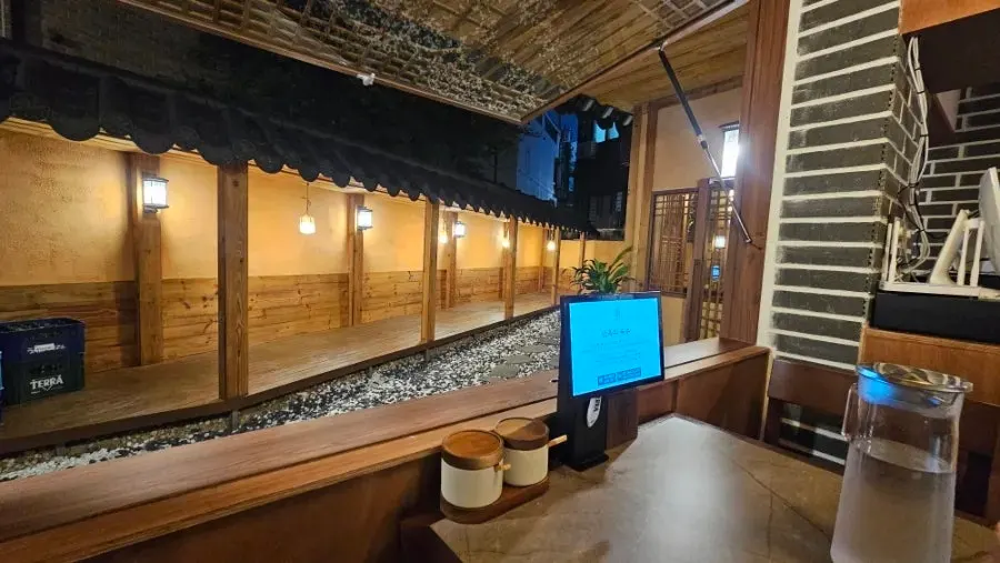 Window seat overlooking the courtyard through floor-to-ceiling glass, with ordering tablet