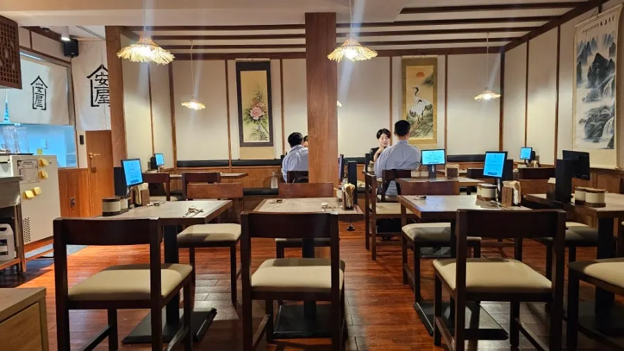 Anok's interior table seating with folk paintings and hanging scrolls on the wall