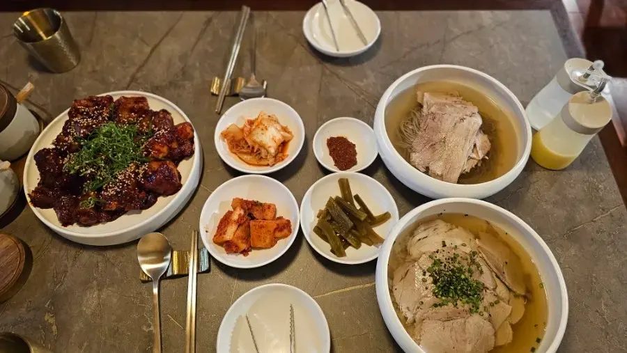 A table set with Pyongyang naengmyeon, gomtang, and pork tail jjim