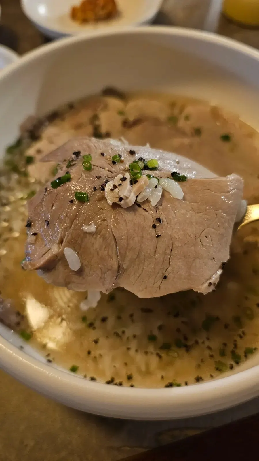 A spoonful of rice topped with a piece of boiled pork