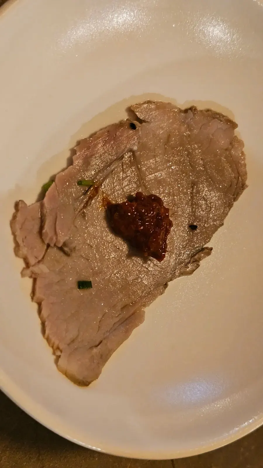 A piece of boiled pork topped with spicy sauce