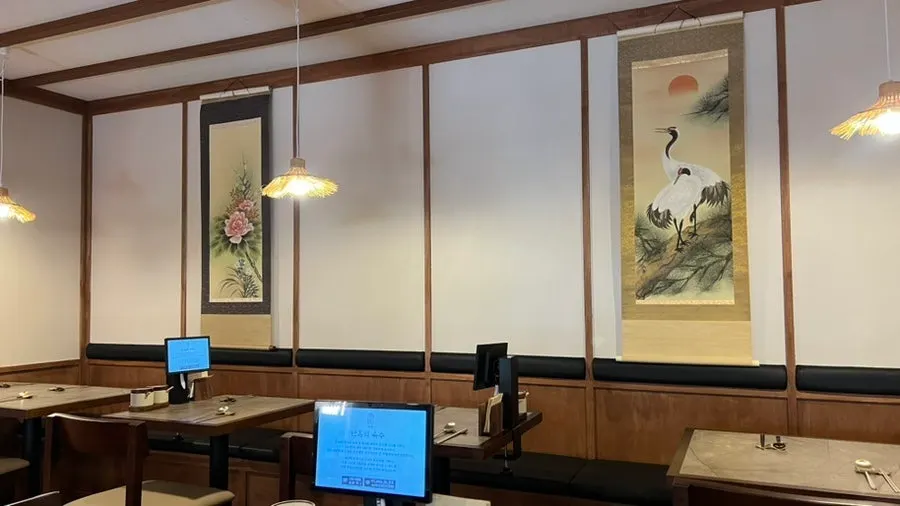 Interior with Korean-style lighting and kitchen visible through the curtains