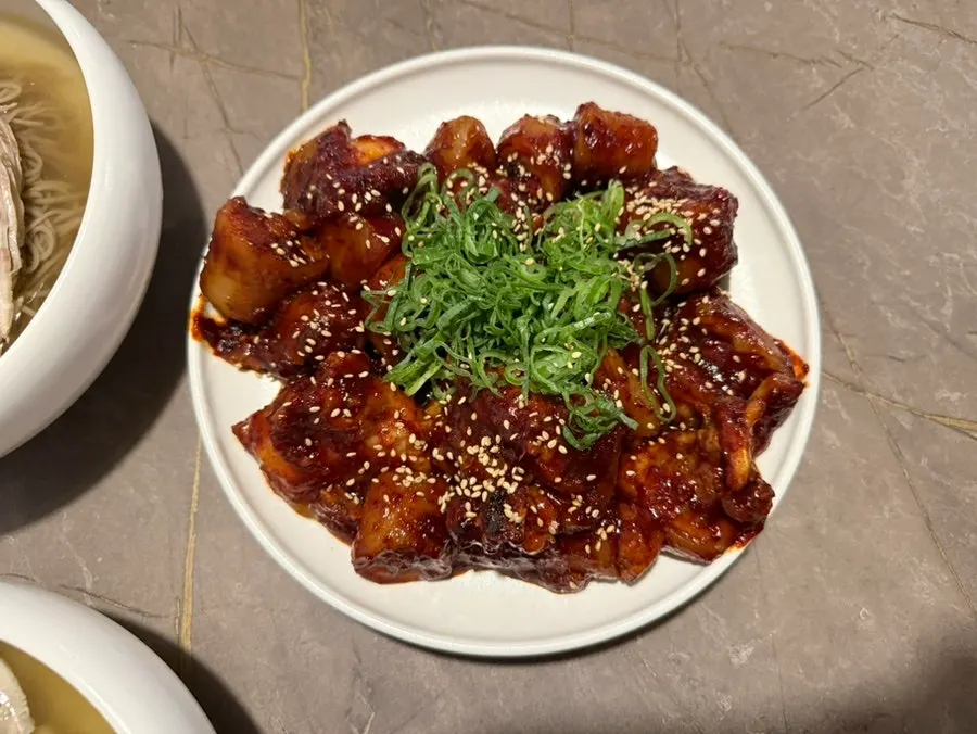 파와 함께 담긴 매콤한 돼지꼬리찜
